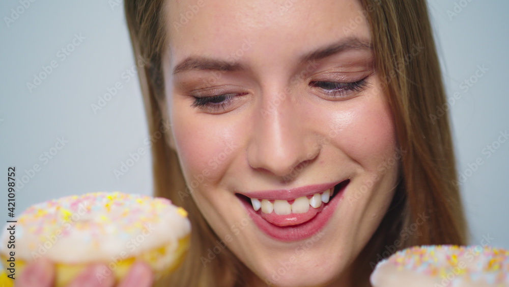 Closeup joyful woman eating donut with big appetite on grey background. Closeup joyful woman eating donut with big appetite on grey background.