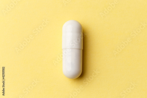 Pharmaceutical medicine pills, tablets and capsules on colourful yellow background. Top view. Flat lay. Copy space. Medicine concepts. Minimalistic abstract concept. White medicine capsule