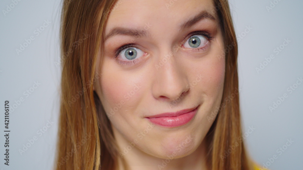 Closeup surprised woman smiling at camera on grey background. Funny girl face Closeup surprised woman smiling at camera on grey background. Funny girl face