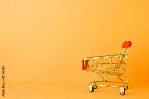 close-up of shopping trolley on Orange background with some copy space