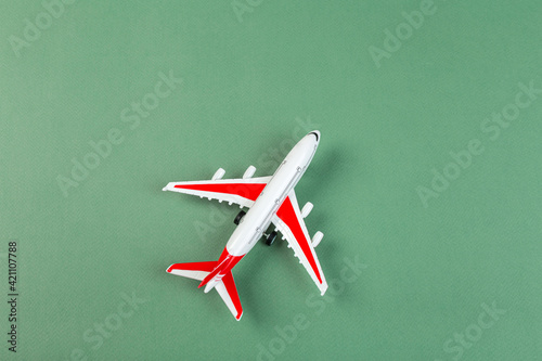 plastic model of an airplane with red wings. tourism and travel concept. green background top view