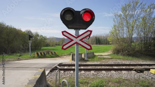 Train level crossing in the outskirts of the city in spring. Traffic lights and rail squeal at train level crossing. 