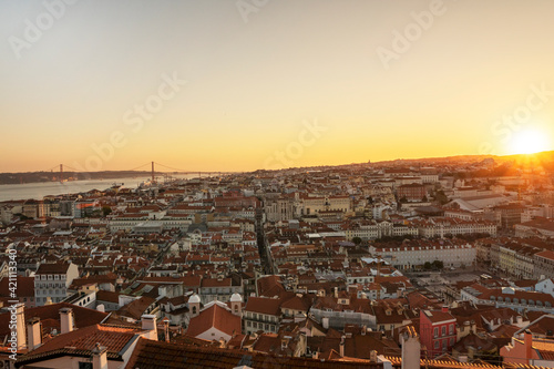 Beautiful yellow sunset in Lisbon  Portugal. Sun rays over red rooftops. Traveling seatination. Romantic vacation in beautiful city.