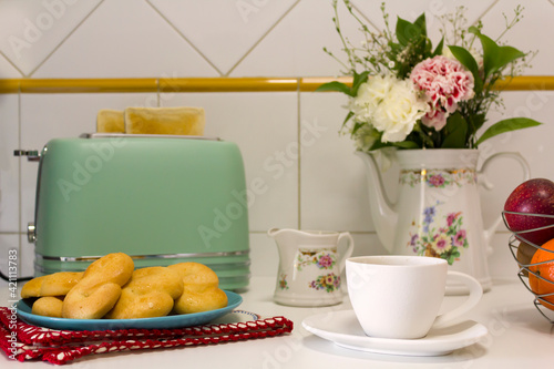 Breakfast table with toasted bread, cookies, coffee and fresh flowers