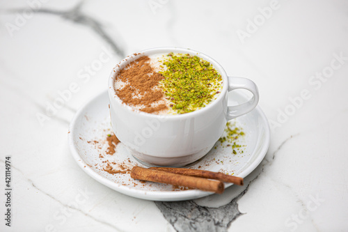 salep, sahlep, white cup Sahlep, Turkey's milk hot drink with cinnamon powder and antes Fist of autumn winter drink, marble background photo