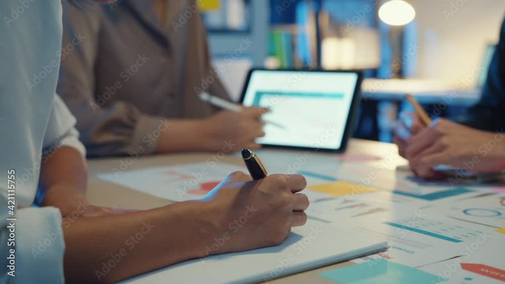 Group of Asia young creative people in smart casual wear discussing business brainstorming meeting ideas mobile application software design project in modern night office. Coworker teamwork concept.