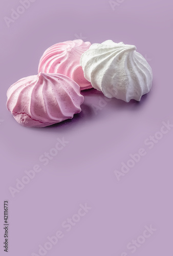 Pink and white meringue on a purple background. Place for your text. High quality photo
