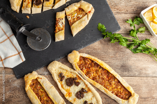 Kasarli sucuklu pide and kiymali pide are traditional Turkish flatbreads similar to pizza with meat and cheese toppings. They are served with lemon and parsley.