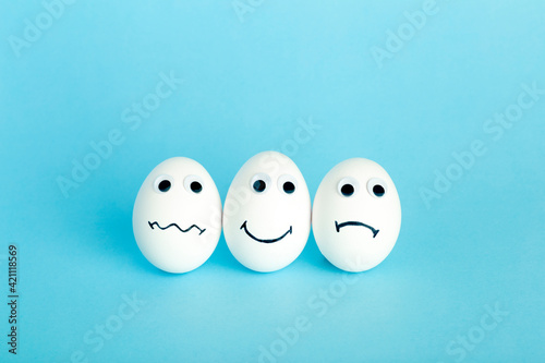 Fun creative food for kids. Eggs minimal concept. White funny eggs for breakfast on a colored background