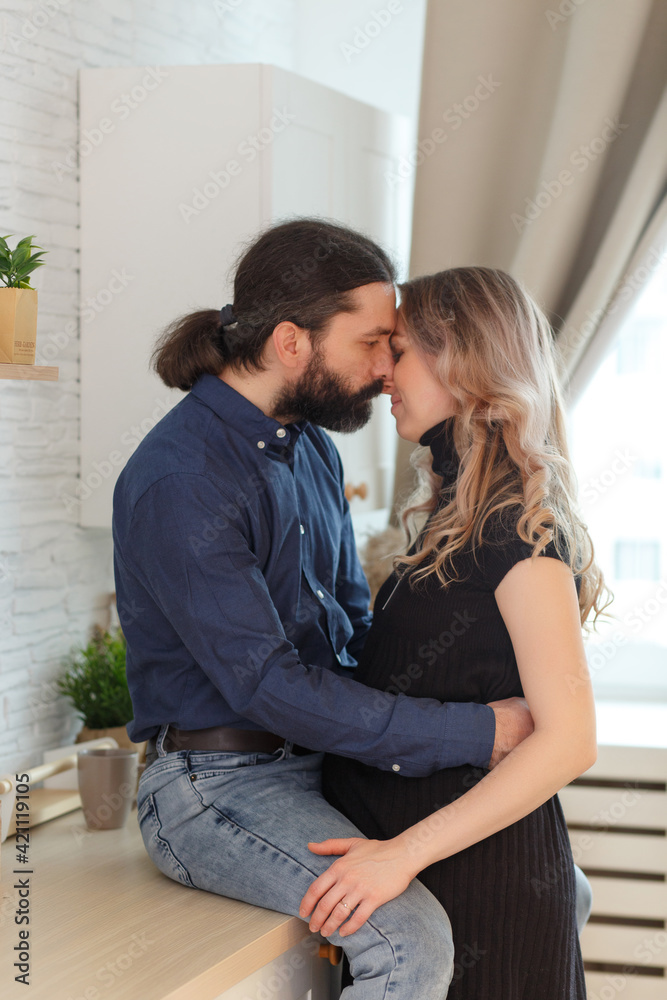 Man embracing pregnant partner in kitchen. Man embracing pregnant partner in kitchen.
