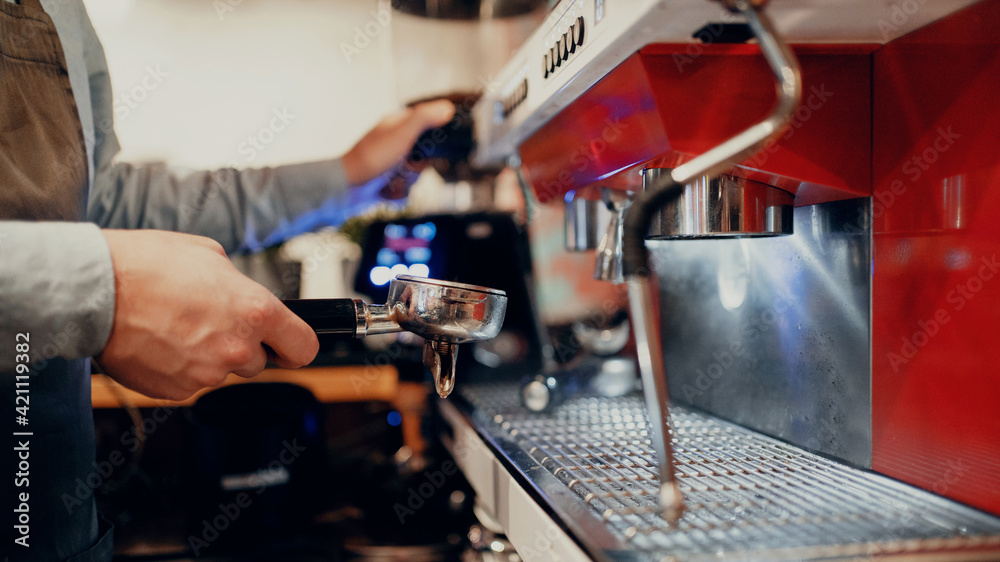 The barista makes coffee in the coffee machine. Works in his small business restaurant cafe. Clothing apron uniform of the bar staff. Copy space. Modern interior.