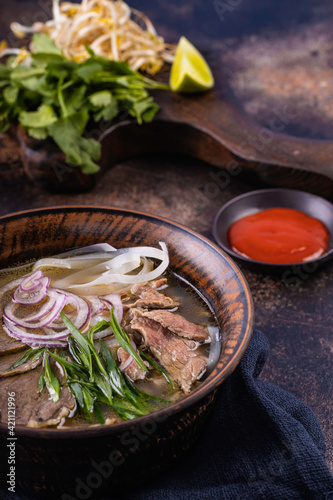 Pho Bo Vietnamese fresh rice noodle soup with beef, onions, lime, herbs and chili. Asian cuisine.