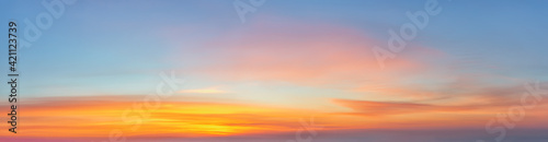 Scenic golden orange clouds against azure sky just before sunrise. Panoramic shot of bright dawn sky. Beautiful pastel colored morning skyscape. The new day beginning. Idyllic paradise heaven. © Maryia