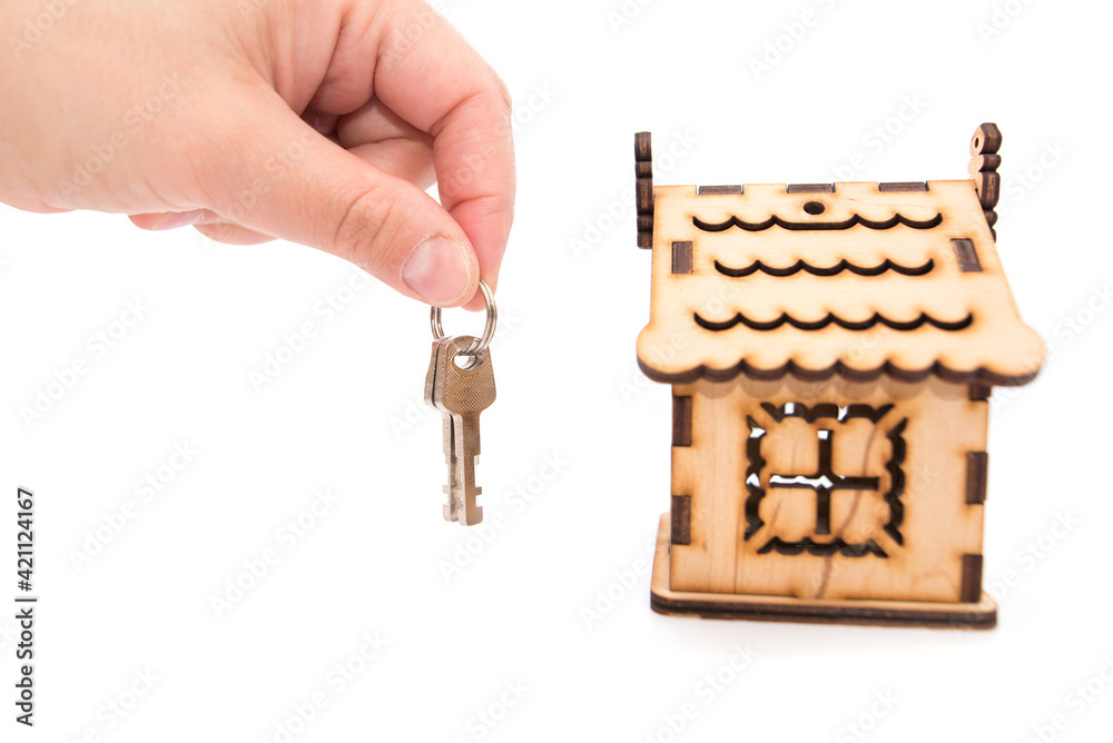 Obraz premium keys in hand and a wooden house on a white background.