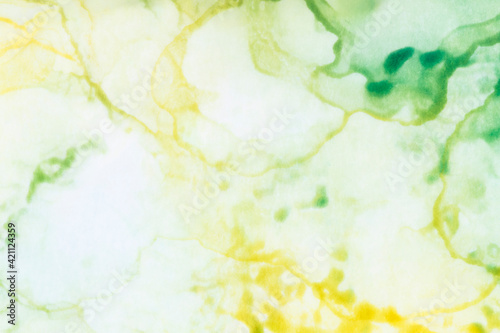 Macro close-up of blurry yellow and green alcohol ink layers and splashes, abstract background. Fluid ink, colorful full frame textured background. Vibrant color. Art for design.