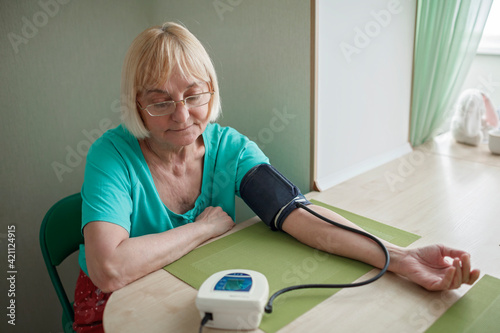 Senior adult using medical electronic device and measuring blood pressure at home, health care and treatment