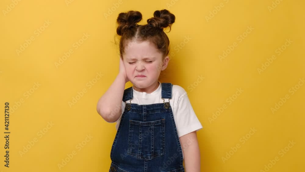 Frowning caucasian little girl kid touch ear closed it with finger hurt suffers from earache strong pain, isolated on yellow background, preschool child look at camera annoyed by loud noise concept Frowning caucasian little girl kid touch ear closed it with finger hurt suffers from earache strong pain, isolated on yellow background, preschool child look at camera annoyed by loud noise concept
