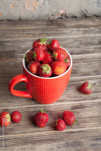 Fresh organic strawberry in red cup on wooden background. Healthy breakfast. Natural farming. Growing fruit. 