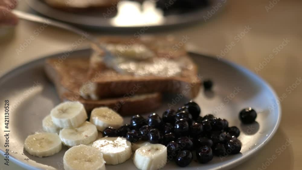 Female hand slowly spreading mashed bananas on french toast Female hand slowly spreading mashed bananas on french toast