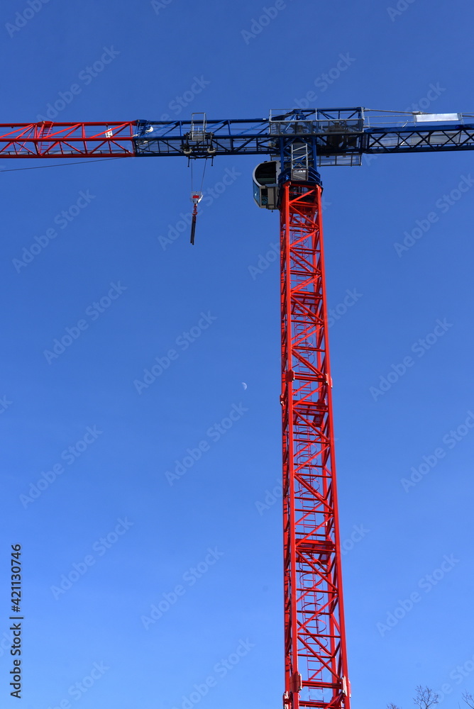 Feuerroter Baukran vor strahlend blauem Himmel Feuerroter Baukran vor strahlend blauem Himmel