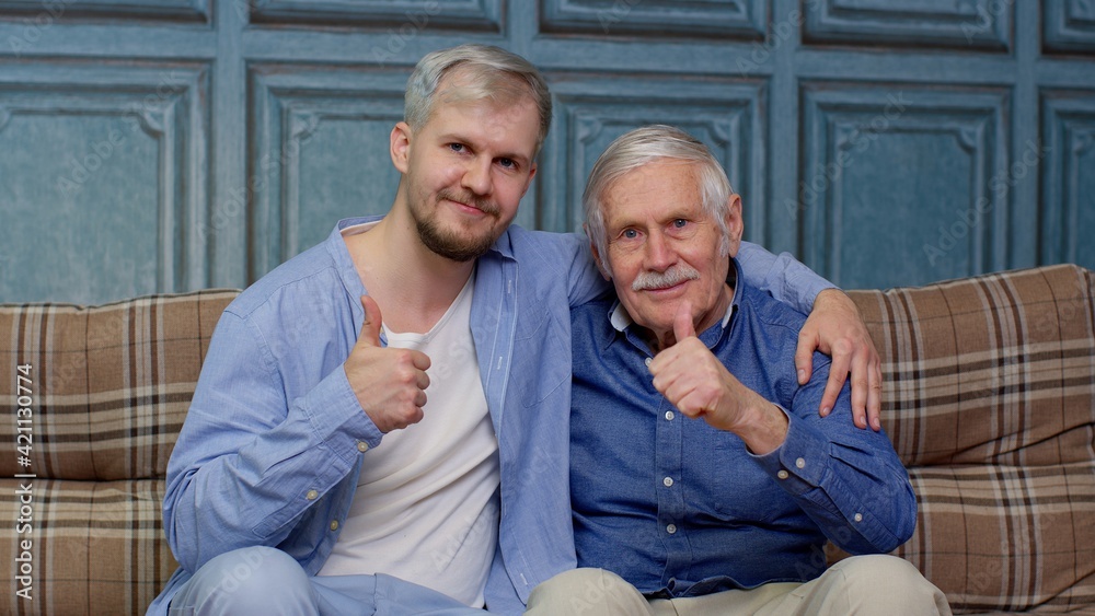 Happy different male generations family of senior father and adult son or grandson showing thumbs up Happy different male generations family of senior father and adult son or grandson showing thumbs up