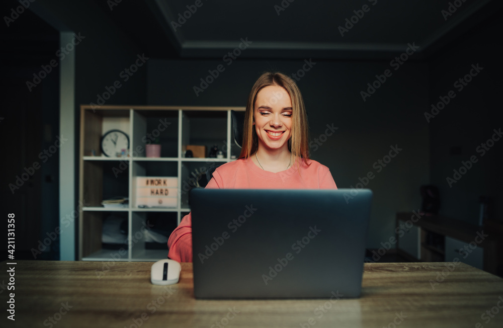 Happy woman working at home at internet table on laptop with smile on face looking at screen. Remote work Happy woman working at home at internet table on laptop with smile on face looking at screen. Remote work