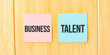 Inscription BUSINESS TALENT on pink and blue square sticky sticker on wooden wall