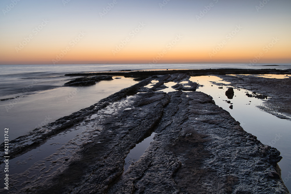 beautiful sunrise on the beach with rocks, located in Alicante, Spain.