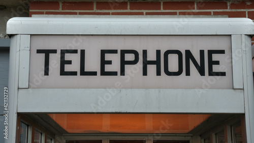 sign at the top of an old telephone booth