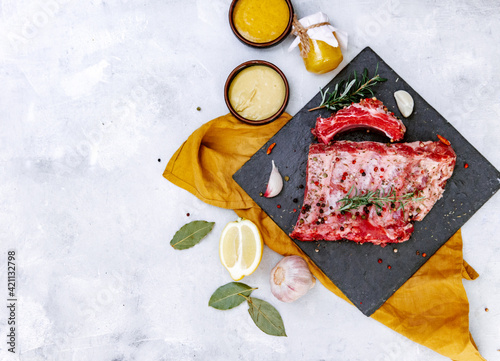 Raw pork ribs, fresh meat with mustard sauce and lemon, top view, flat lay, copy space photo