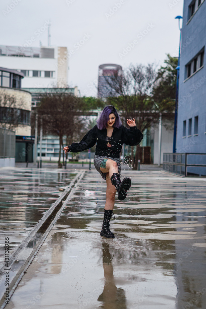 Young woman with purple hair splashing water. Kicking water