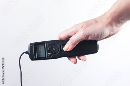 Fotografie Hand holding remote control shutter switch of DSLR mirrorless camera on white background