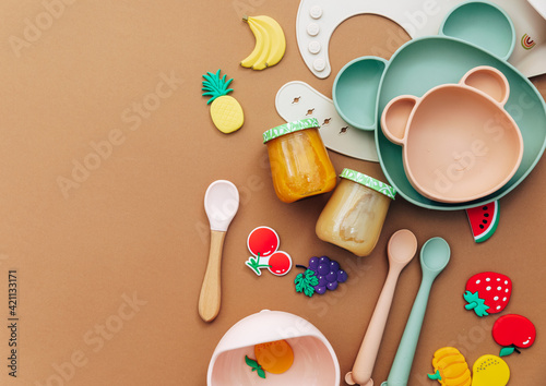 Bright silicone dishware on light background. Serving baby, first feeding concept. Flat lay, copy space, top view