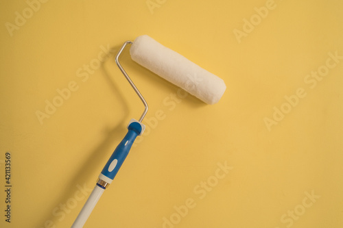 White Paint Roller on a Yellow Wall