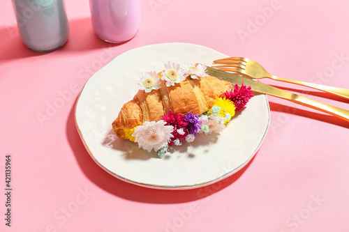 Composition with tasty croissant and flowers on color background