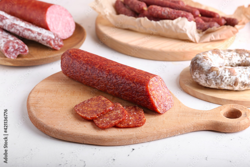 Board with tasty salami on light background Board with tasty salami on light background