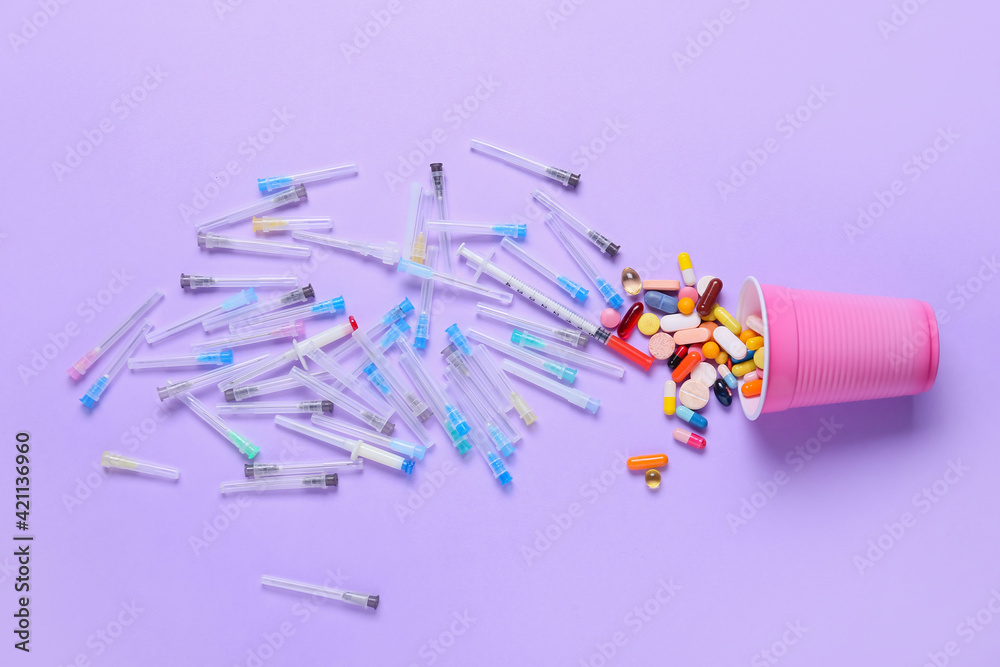 Cup with many pills and syringes on color background Cup with many pills and syringes on color background