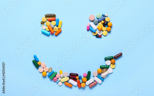 Happy face made of different drugs on color background. Addiction concept