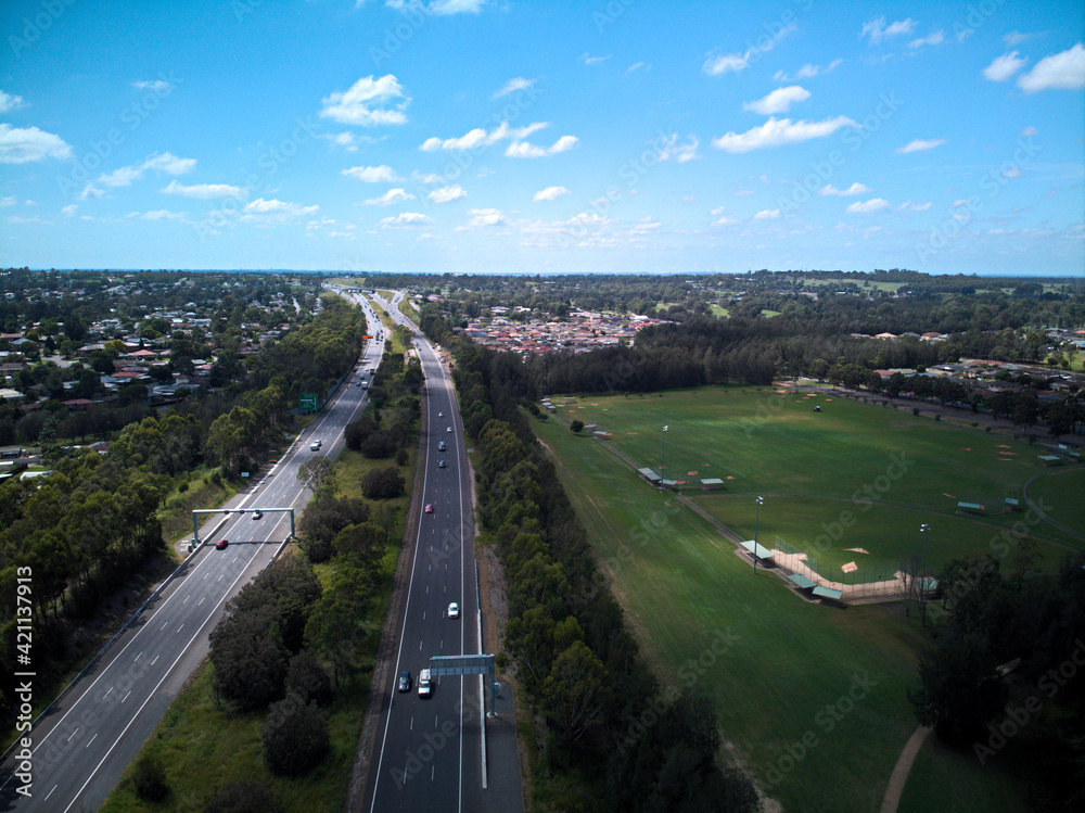 Aerial image of the M4 motorway facing east from Glenmore Park, with green sporting fields and suburban homes in the background.