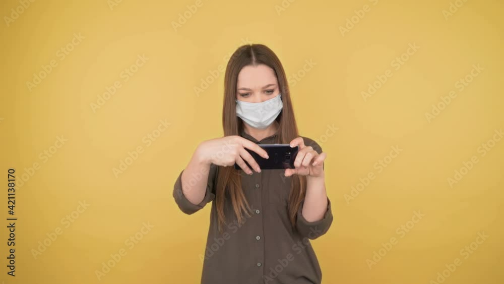 Portrait with cute young adult woman browsing web pages on yellow background