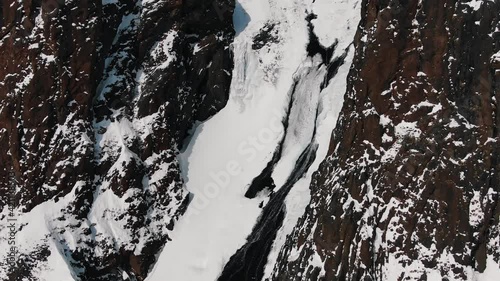 Wallpaper Mural Aerial view of a mountain frozen waterfall on steep slopes and cliffs in the highlands. Icy streams of water fall from a great height. Global warming and melting glaciers. Torontodigital.ca