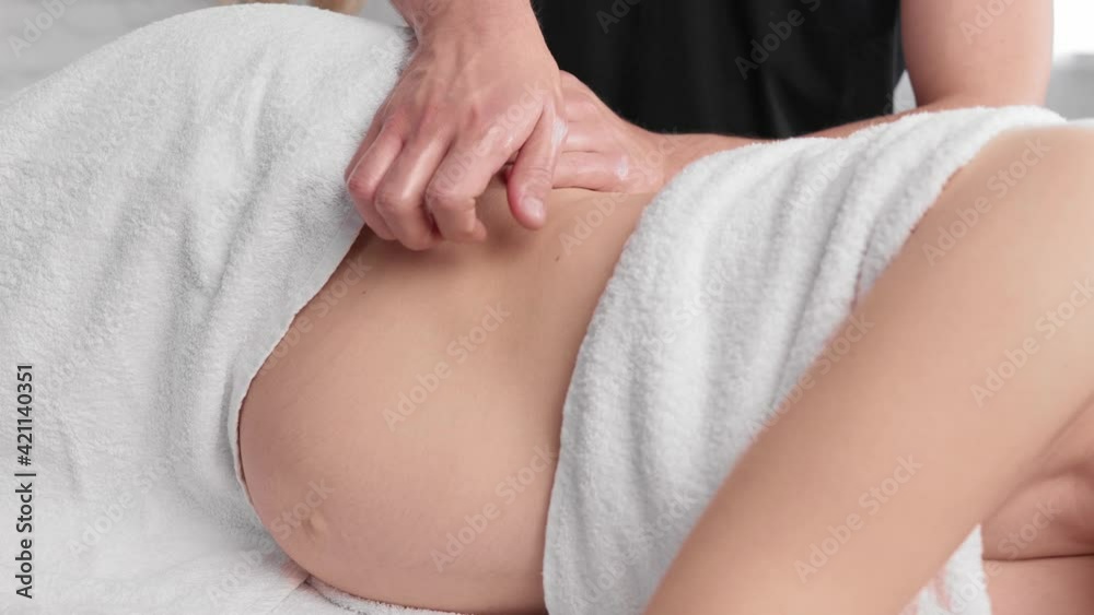 Video of beautiful young physiotherapist massaging tummy on pregnant woman on a stretcher at home.