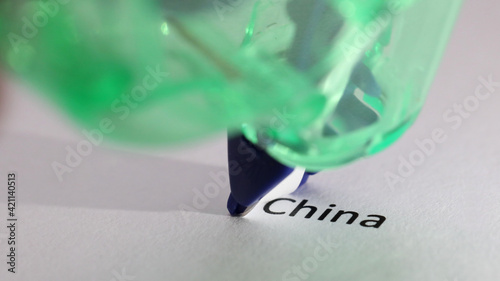 The removal, hiding, covering up of the word or text 'China'. Poor, failed or failing trade and economic relationship with China concept. Correction tape removing China photo