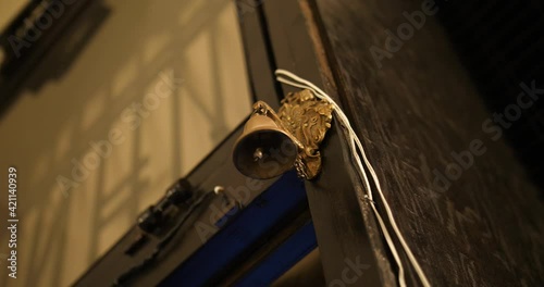 Oldschool golden bell above a door of a shop moving and tinkling. Close-up shot