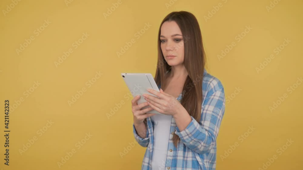 Young serious young adult woman watching pages on tablet Young serious young adult woman watching pages on tablet