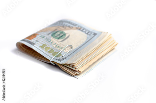A wad of folded American dollars money isolated on white background. The new hundred-dollar bill is on top of the other banknotes.
