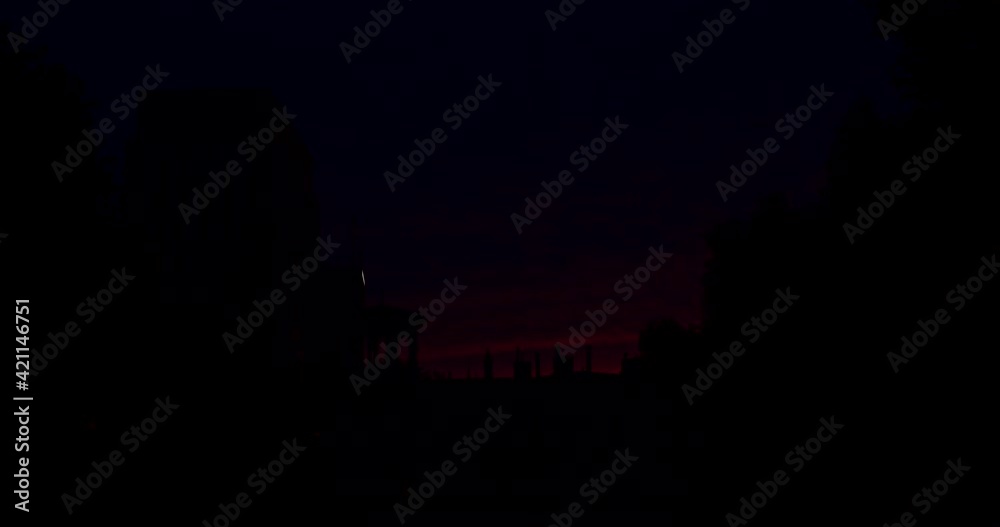 Sunrise in purple and red colors in the city behind buildings and towers in Timelapse. Sunrise in purple and red colors in the city behind buildings and towers in Timelapse.
