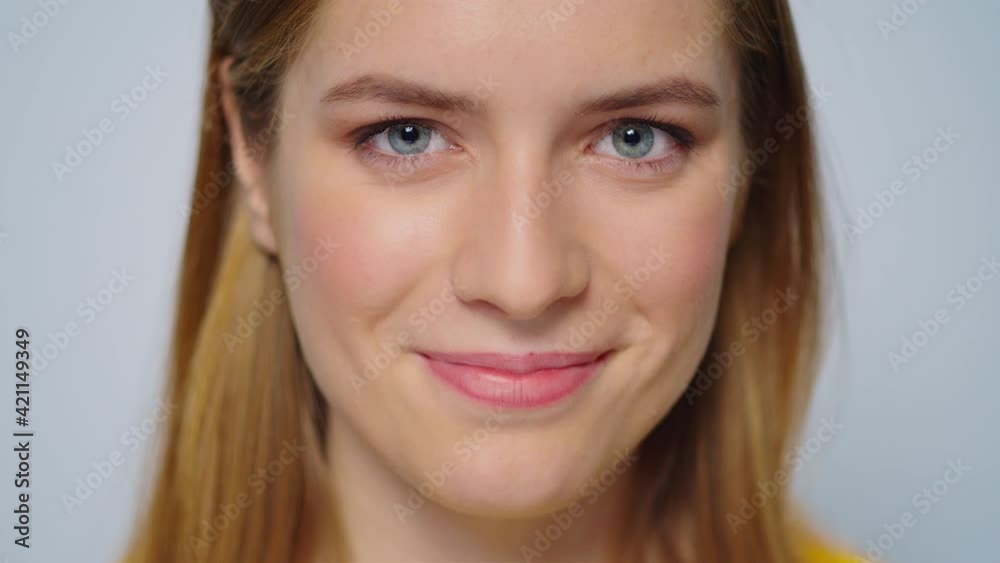 Closeup smiling attractive woman looking at camera on grey background. Closeup smiling attractive woman looking at camera on grey background.