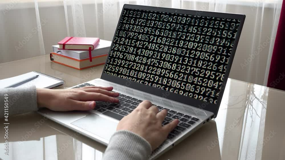 Binary code on the monitor screen. The girl working at home office hands on keyboard.