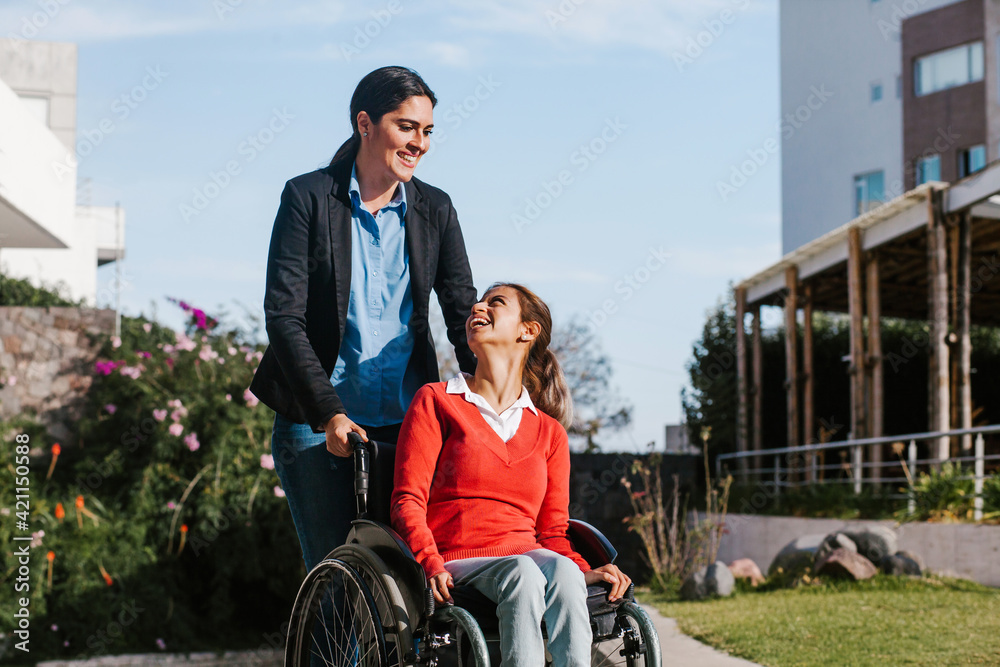 mexican woman in wheelchair and her friend having fun outdoors in Mexico mexican woman in wheelchair and her friend having fun outdoors in Mexico